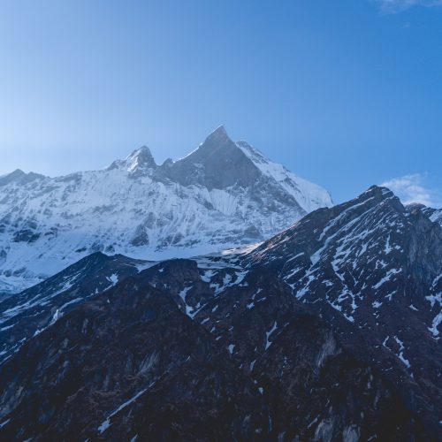 Stunning view of Machapuchare peak with a clear blue sky in Nepal's Annapurna range.