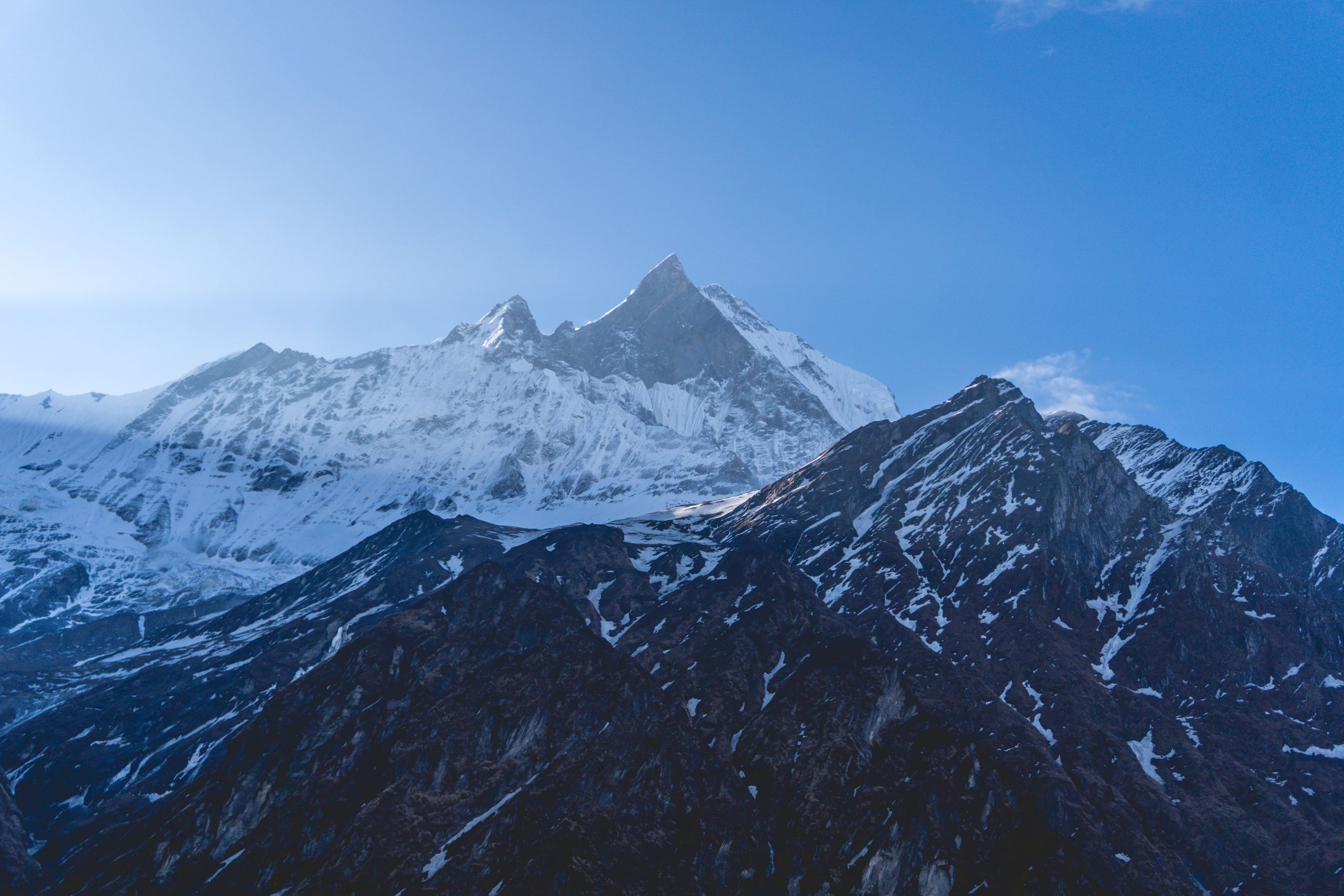Stunning view of Machapuchare peak with a clear blue sky in Nepal's Annapurna range.